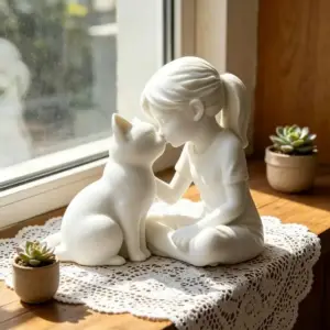 Weiße Figur eines Mädchens mit Katze auf einer Spitzendecke am Fenster