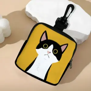 Gelbes Münzetui mit schwarz-weißer Katze und Karabiner auf einem Podest