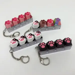 Vier Schlüsselanhänger mit Katzenpfoten-Tastenkappen in Rosa und Schwarz auf weißem Untergrund