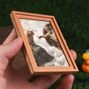 Kleiner Rahmen mit Katze auf einem Felsen im Wolkenhimmel, in einer Hand gehalten