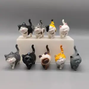 Mehrere kleine Katzenfiguren in verschiedenen Fellfarben auf grauem Hintergrund