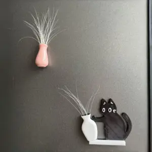 Schwarze Katze mit weißer Vase und feinen weißen Federn als Magnet am Kühlschrank