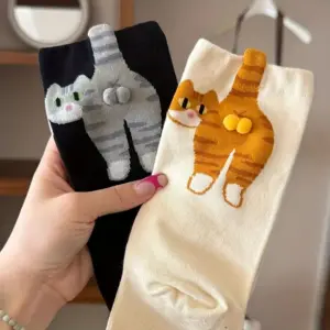 Schwarze und cremefarbene Socken mit aufgesticktem Katzenpopo und Bommeln