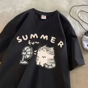 Schwarzes T-Shirt mit Aufdruck Katze vor Ventilator auf weichem Untergrund