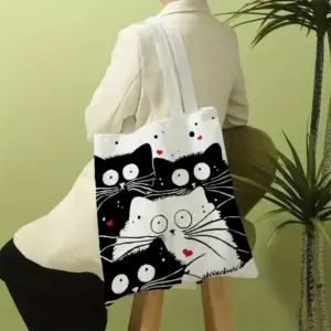 Frau trägt weiße Stofftasche mit Motiv aus schwarzen und weißen Katzen über der Schulter