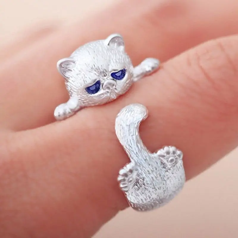 Silberfarbener Ring mit Katzenfigur und blauen Augen, am Finger getragen