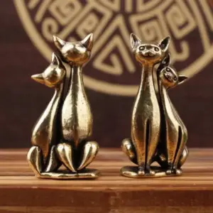 Zwei Katzenpaar-Figuren in goldfarbenem Look stehen auf einem Holztisch