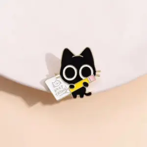 Schwarze Katzen-Anstecknadel mit großen Augen, hält einen gelben Stift