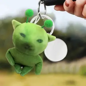 Grüne Katzenfigur mit Fühlern als Schlüsselanhänger, in der Hand gehalten