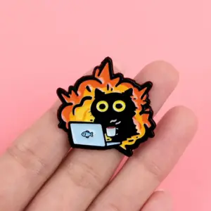 Emaille-Pin mit Katze vor Flammen am Laptop mit Tasse, in der Hand gehalten